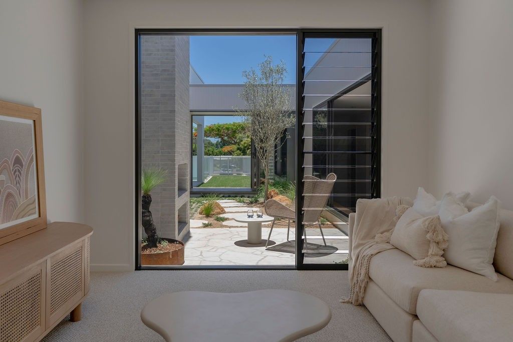 Black-framed aluminium sliding door opening onto a Sunshine Coast courtyard